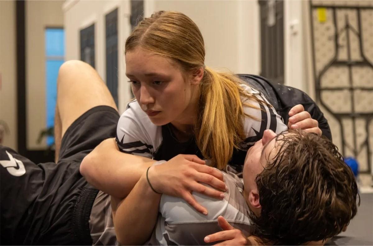 Woman demonstrating effective ground control during a hands-on self defense class.