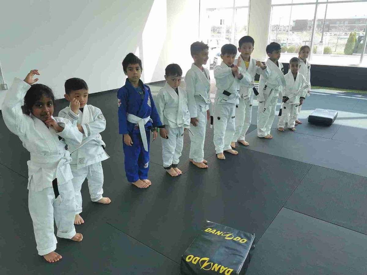 Children lined up in uniforms practicing beginner self defense techniques in a structured martial arts class.