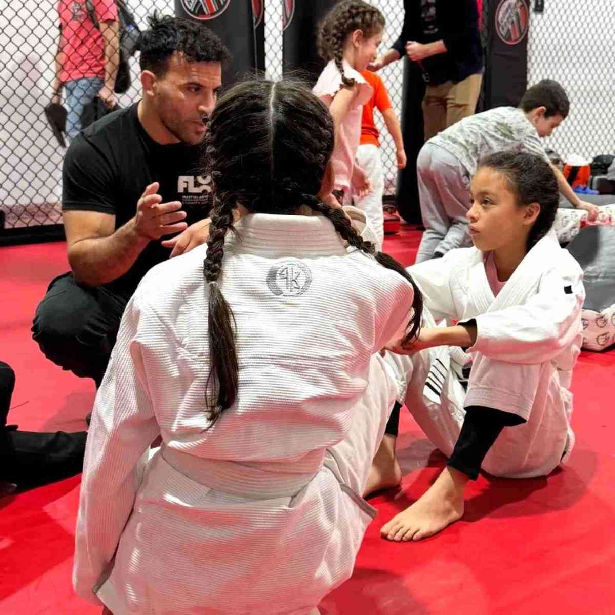 Instructor coaching kids on foundational self defense drills inside a professional training facility.